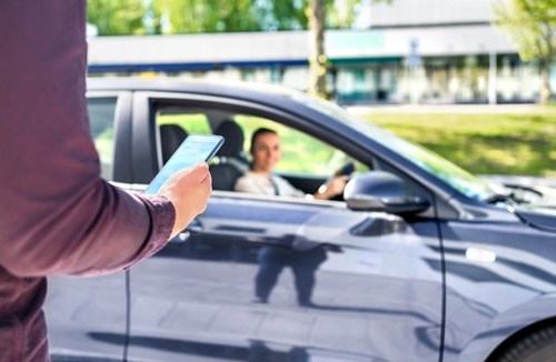 Female rideshare driver pulling up to passenger checking phone — Roswell rideshare accident lawyer assisting rideshare accident victims, Contact a Roswell rideshare accident lawyer at Horst Shewmaker LLC today.