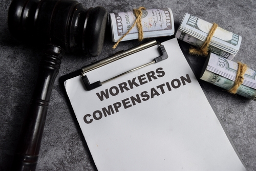 A gavel and money by a workers' compensation claims from illustrating the workers' compensation claim process.