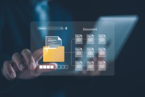 A lawyer from Horst Shewmaker in a dark business suit reaches one hand forward to touch a glowing translucent digital interface floating in the air in front of a blurred tablet device displaying a yellow file folder icon labeled LOADING with a progress bar beneath it connected by branching lines to nine individual document icons arranged in a three-by-three grid under the heading Document with a search bar visible at the top — representing the digital organization and retrieval of medical records- police reports- and legal paperwork needed to build a strong car accident claim.