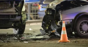 Two cars with broken car pieces on a road due to a speed-related accident by a reckless driver.